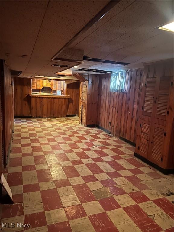 basement featuring wooden walls and bar area