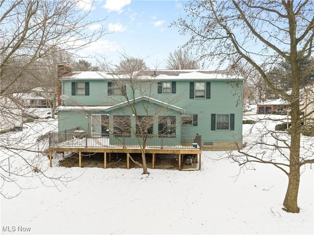 snow covered rear of property with a wooden deck