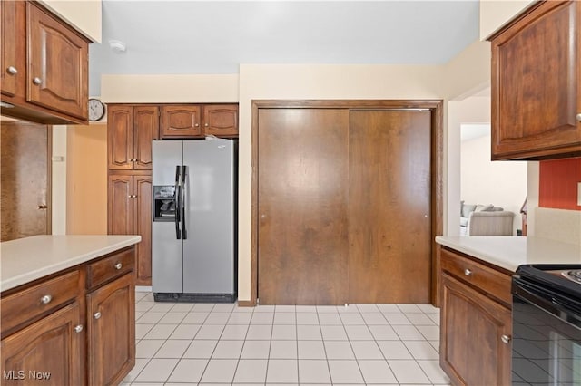 kitchen with light tile patterned flooring, black electric range oven, and stainless steel fridge