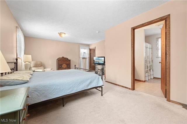 bedroom with ensuite bathroom and light carpet