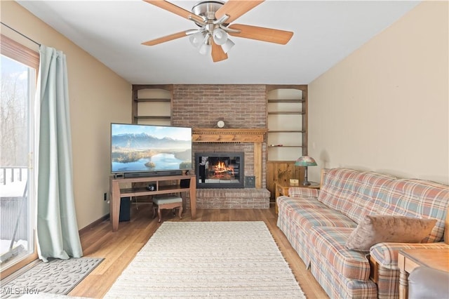 living room with a fireplace, ceiling fan, and light hardwood / wood-style floors