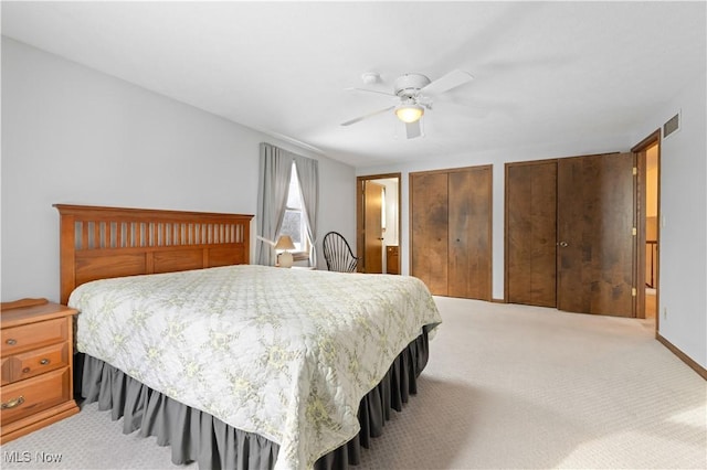 bedroom with light carpet, multiple closets, and ceiling fan