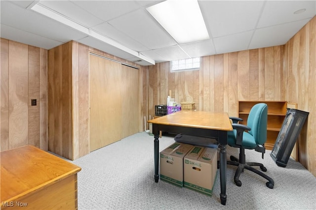 carpeted office space with wooden walls and a drop ceiling