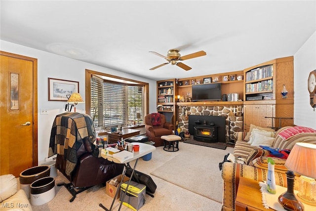 carpeted living room featuring ceiling fan, built in features, and a wood stove