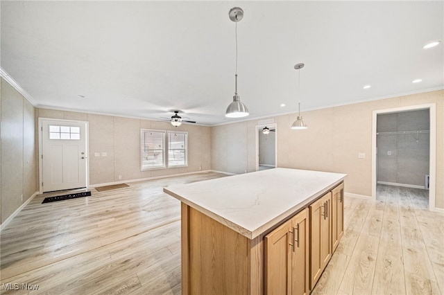 kitchen featuring crown molding, hanging light fixtures, light hardwood / wood-style flooring, a kitchen island, and ceiling fan