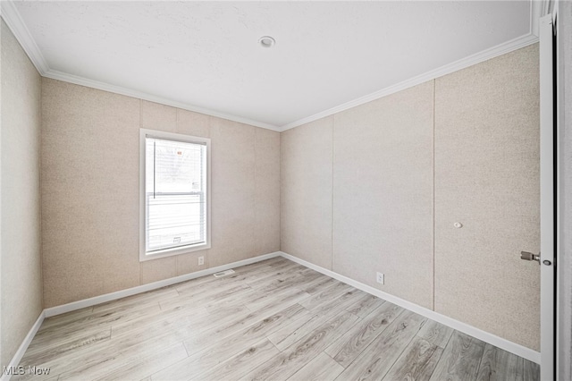 empty room with ornamental molding and light wood-type flooring