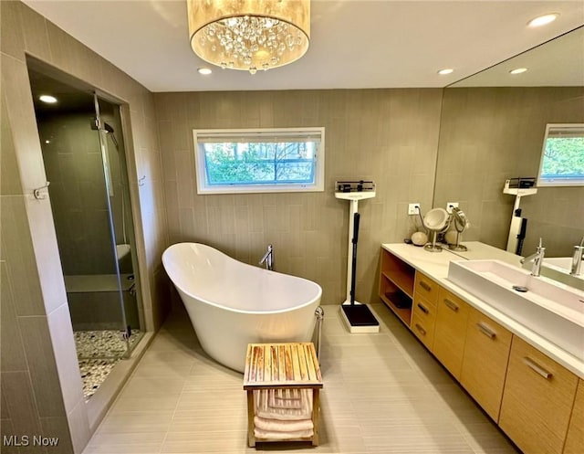 bathroom with a notable chandelier, separate shower and tub, a healthy amount of sunlight, and vanity