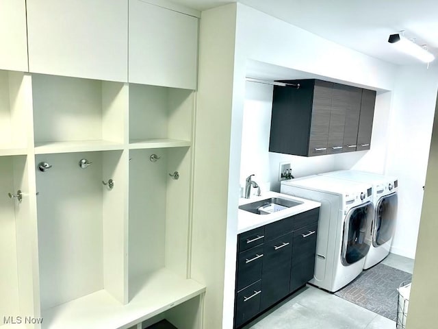 laundry area featuring sink, washing machine and dryer, and cabinets