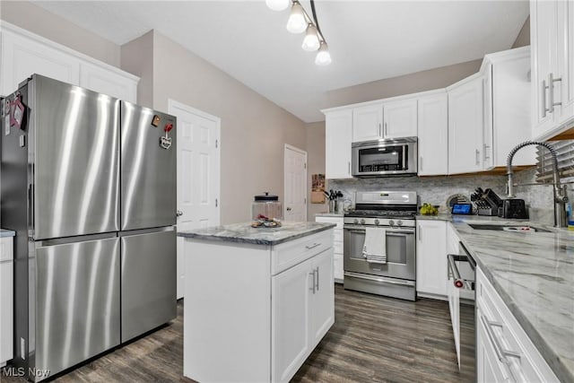 kitchen featuring tasteful backsplash, a kitchen island, white cabinetry, appliances with stainless steel finishes, and sink