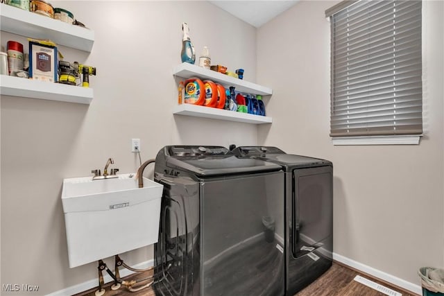 clothes washing area with sink, dark wood-type flooring, and washing machine and dryer