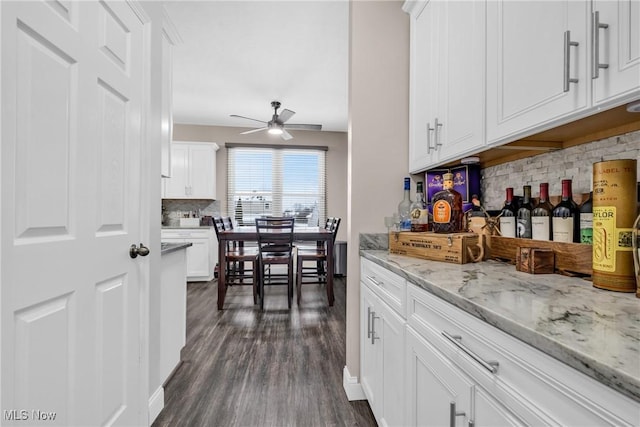 kitchen featuring white cabinets, ceiling fan, light stone countertops, and tasteful backsplash