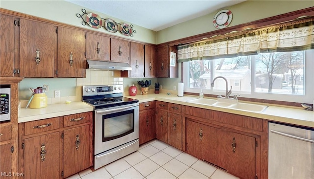 kitchen featuring light tile patterned floors, backsplash, appliances with stainless steel finishes, and sink