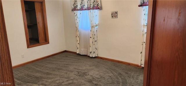 unfurnished room featuring dark colored carpet