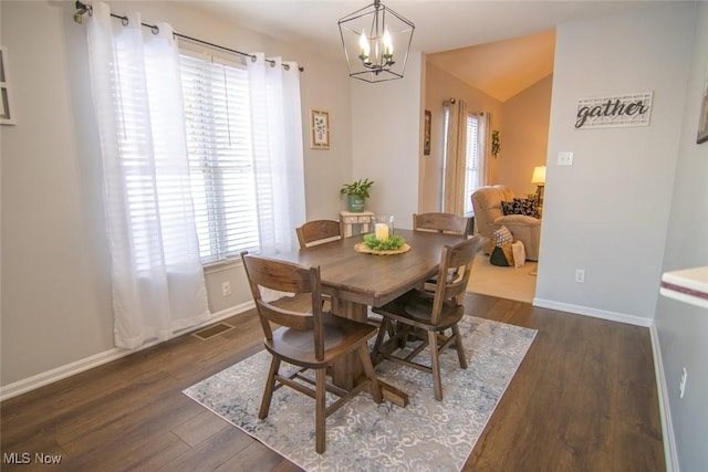 dining space featuring dark hardwood / wood-style flooring, an inviting chandelier, and vaulted ceiling