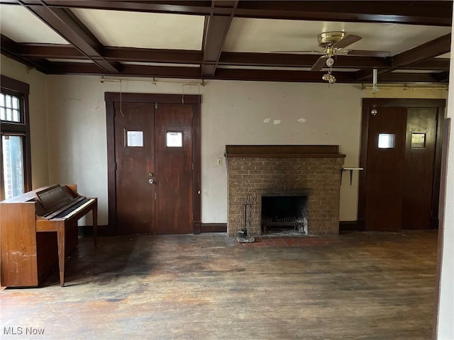 unfurnished living room featuring a fireplace, dark hardwood / wood-style flooring, coffered ceiling, ceiling fan, and beam ceiling