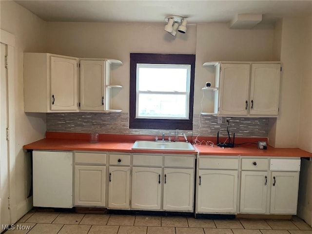 kitchen with sink, light tile patterned floors, white cabinets, and decorative backsplash