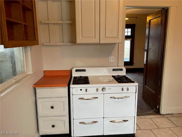 kitchen featuring double oven range, light tile patterned flooring, and white cabinets