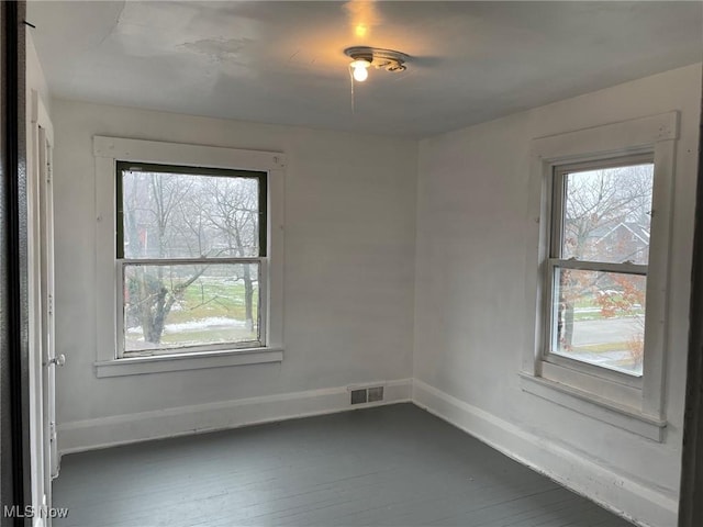 unfurnished room with a healthy amount of sunlight and dark wood-type flooring