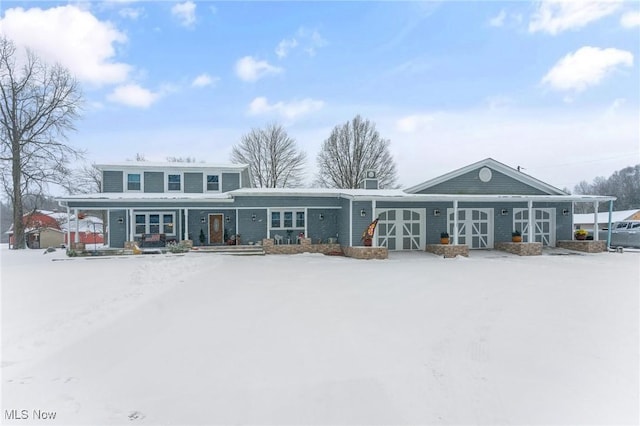 snow covered rear of property featuring a garage