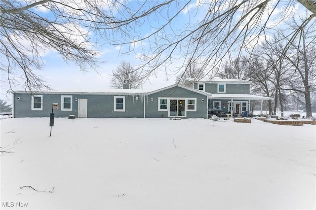 snow covered property featuring covered porch and a chimney