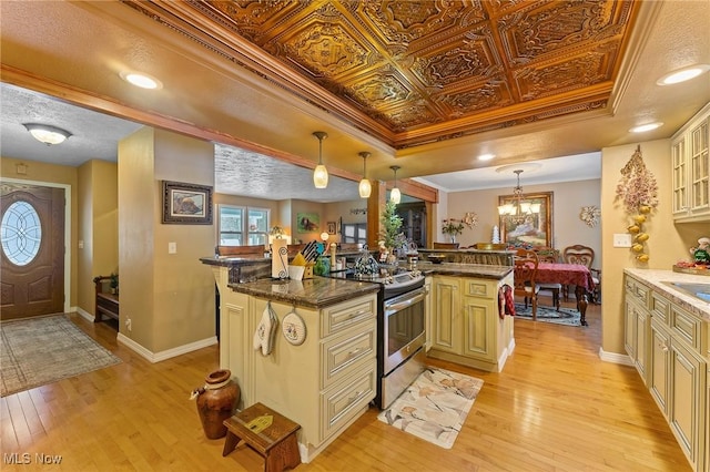 kitchen featuring an ornate ceiling, cream cabinetry, a raised ceiling, ornamental molding, and stainless steel range with electric cooktop