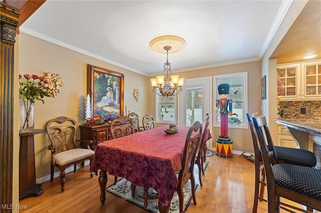 dining area featuring a chandelier, baseboards, crown molding, and light wood finished floors