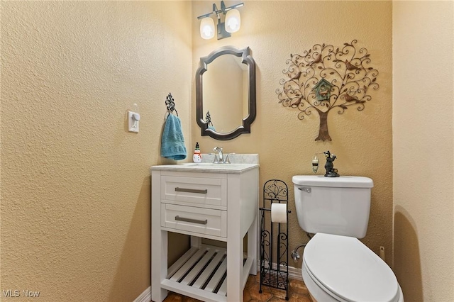 half bath with baseboards, a textured wall, vanity, and toilet