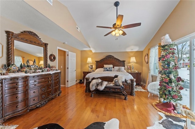 bedroom featuring light wood finished floors, baseboards, visible vents, a ceiling fan, and vaulted ceiling