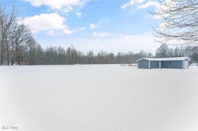 snowy yard with a garage and an outbuilding