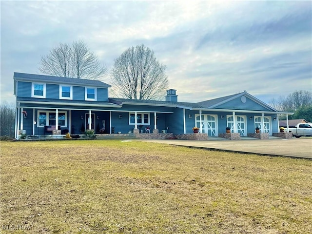 view of front of house featuring a front yard, covered porch, and a chimney