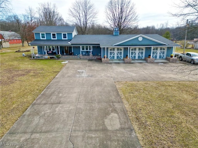 view of front of home featuring a front yard, covered porch, a chimney, and concrete driveway