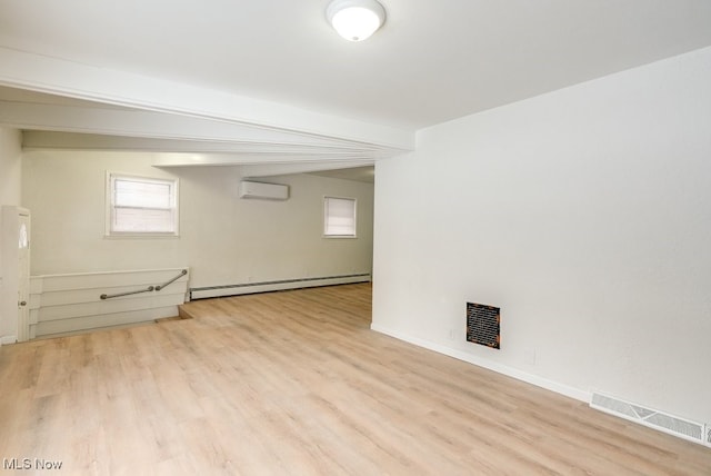 basement with an AC wall unit, a baseboard radiator, and light hardwood / wood-style flooring