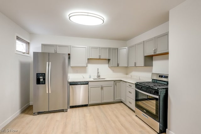 kitchen with stainless steel appliances, gray cabinets, light hardwood / wood-style floors, and sink