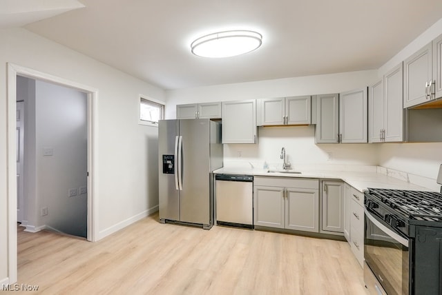 kitchen with sink, light hardwood / wood-style floors, gray cabinetry, and appliances with stainless steel finishes