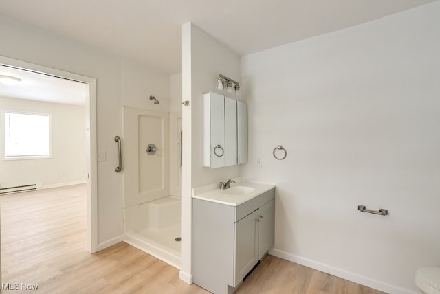 bathroom featuring baseboard heating, walk in shower, wood-type flooring, and vanity