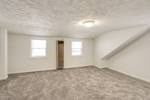 carpeted spare room with a textured ceiling and vaulted ceiling