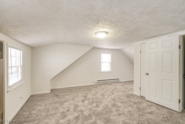 additional living space featuring lofted ceiling, baseboard heating, a textured ceiling, and light colored carpet