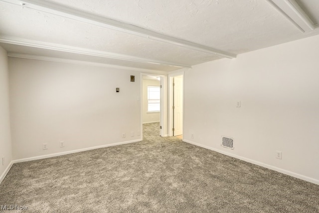 unfurnished room with a textured ceiling, carpet, and beamed ceiling