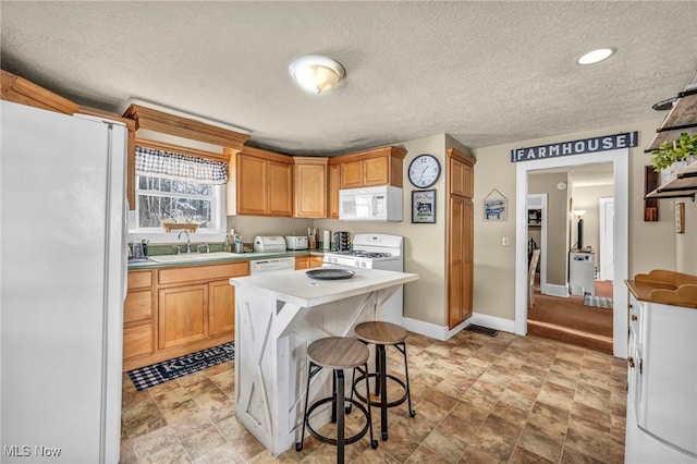 kitchen featuring white appliances, a textured ceiling, a kitchen island, and sink