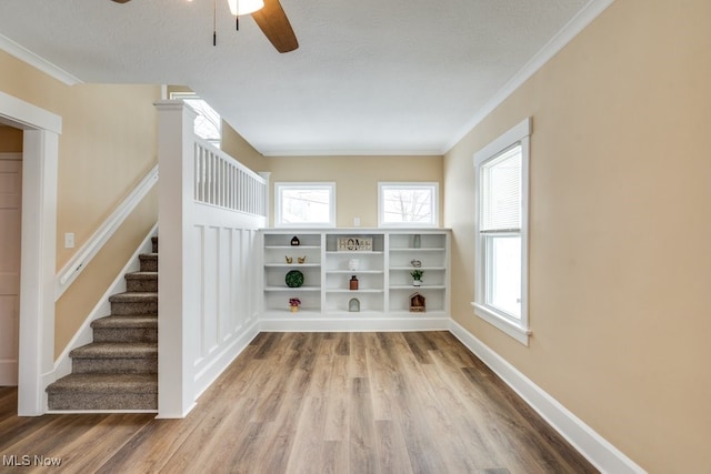 spare room featuring ceiling fan, wood-type flooring, ornamental molding, and a textured ceiling