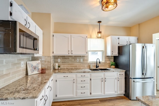 kitchen with sink, decorative light fixtures, appliances with stainless steel finishes, white cabinets, and backsplash