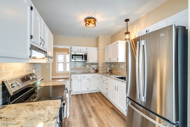 kitchen with stainless steel appliances, white cabinetry, hanging light fixtures, and light stone counters