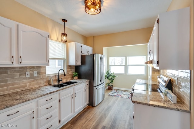 kitchen with pendant lighting, white cabinetry, sink, light hardwood / wood-style floors, and stainless steel appliances