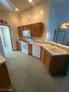 kitchen with white appliances, light carpet, and sink