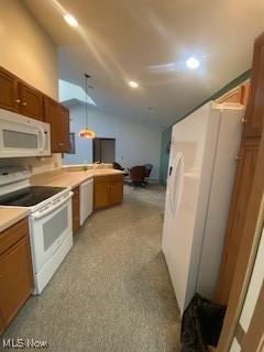 kitchen featuring decorative light fixtures, white appliances, light carpet, and vaulted ceiling