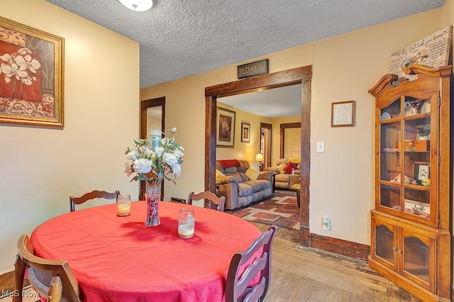 dining space with hardwood / wood-style floors and a textured ceiling