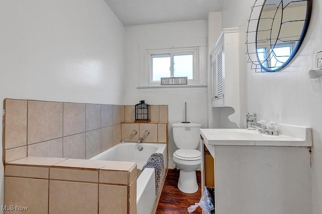 bathroom featuring hardwood / wood-style floors, toilet, a tub to relax in, and vanity