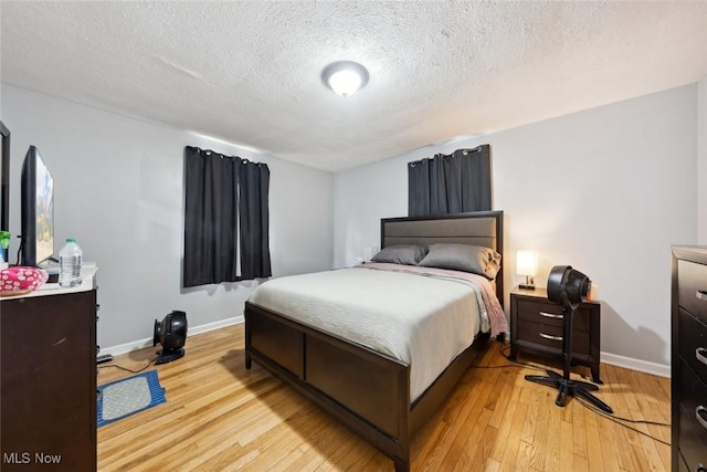 bedroom featuring light hardwood / wood-style floors and a textured ceiling