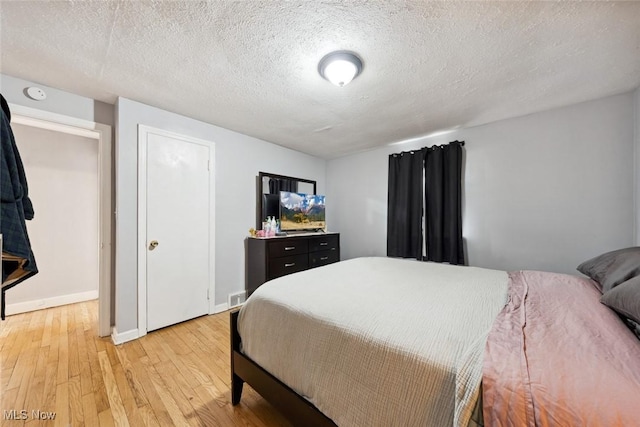 bedroom featuring a textured ceiling and light hardwood / wood-style flooring