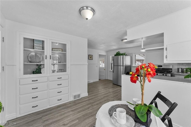 kitchen featuring white cabinets, stainless steel appliances, hardwood / wood-style floors, and a textured ceiling